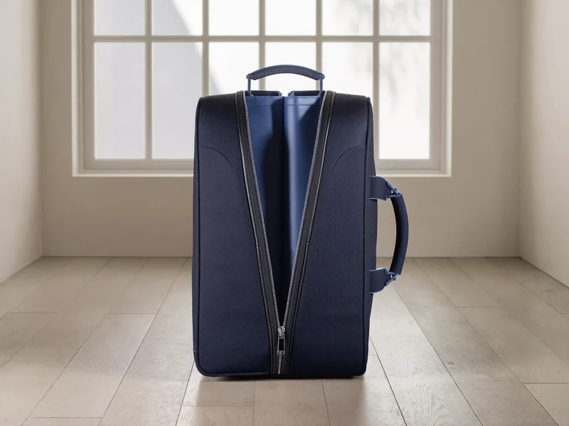 Valise souple bleu marine légèrement ouverte, tissu et fermeture éclair visibles.