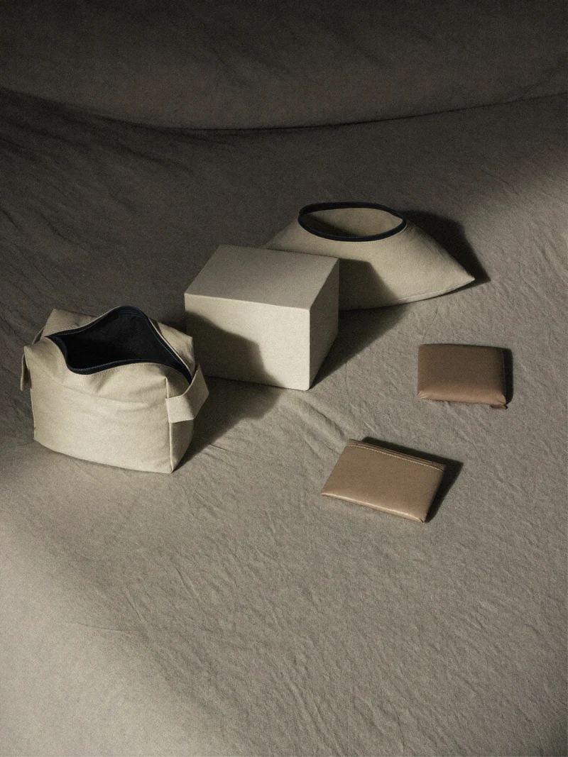 Cubes de rangement, trousse, oreiller de nuque et porte-passeport disposés sur du lin.